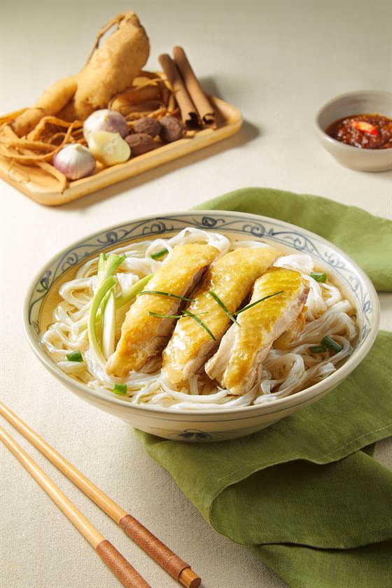 Tô phở gà với thịt gà xé, hành lá và bánh phở trong nước dùng trong.